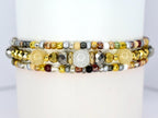 Three beaded bracelets with a variety of colors and textures. The bracelets feature gold, silver, and bronze beads, as well as larger, faceted beads and round, white beads. The bracelets are stacked together.