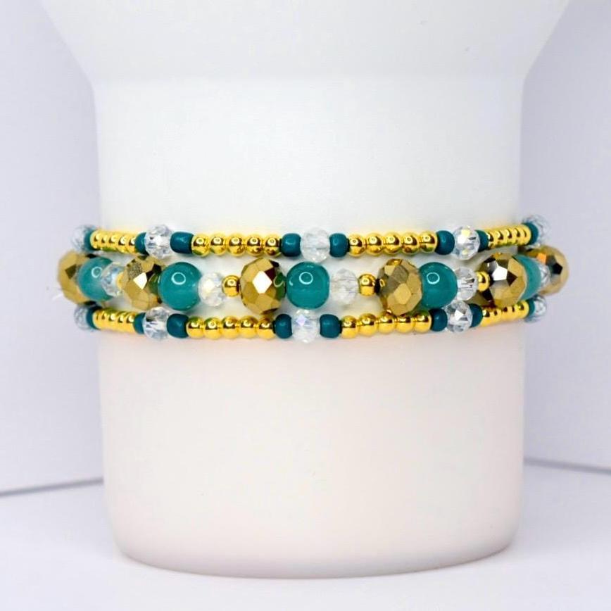 Beaded tumbler bracelet with gold, teal, and clear crystal beads in a layered design. Features faceted metallic gold accents, smooth teal beads, and small gold spacers for a sparkling, elegant look.