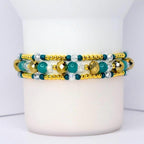 Beaded tumbler bracelet with gold, teal, and clear crystal beads in a layered design. Features faceted metallic gold accents, smooth teal beads, and small gold spacers for a sparkling, elegant look.
