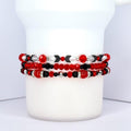 Three beaded bracelets in red, black, and silver. The top bracelet features red and black beads with silver accents and black arrow-shaped beads. The middle bracelet has red and black beads with silver accents. The bottom bracelet is primarily red with black and silver beads.