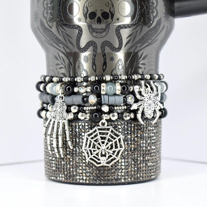Halloween tumbler bracelet in black and silver with spider, web, and skeleton hand charms – spooky beaded wrap for gothic and seasonal drinkware.