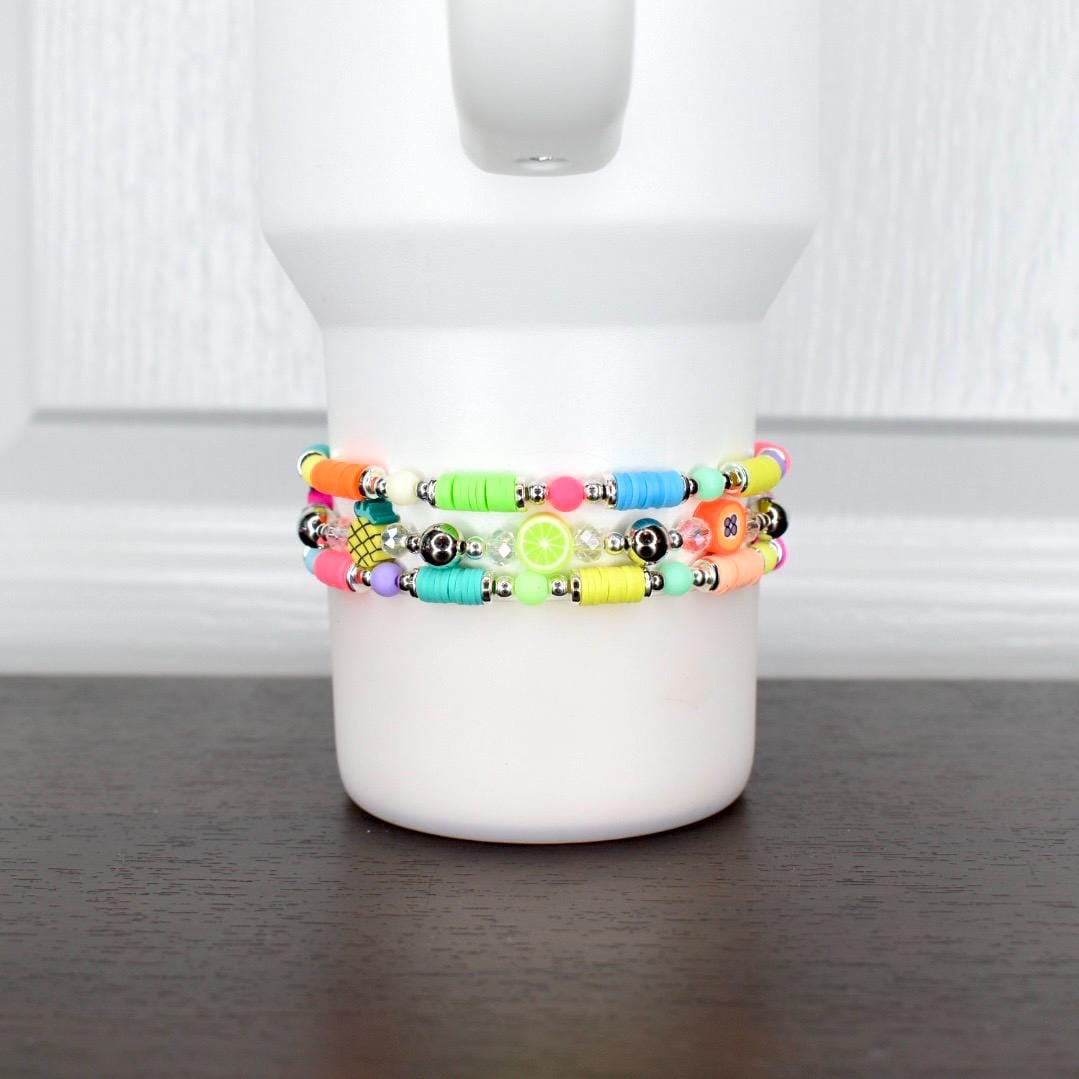 Bright fruity bracelet – neon beaded wrap with strawberry, pineapple, and apple charms, wearable on tumbler or wrist.
