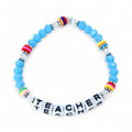 A blue beaded bracelet with the word "TEACHER" spelled out in white letter beads. The bracelet features colorful accent beads with rainbow and striped patterns. The beads are strung on a clear elastic cord.