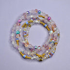 A collection of beaded bracelets in shades of pink, white, and iridescent colors. The bracelets feature a variety of beads, including round, faceted, and pearl-like beads, with gold-colored accents and light blue spacers. The bracelets are arranged in a circular pattern.