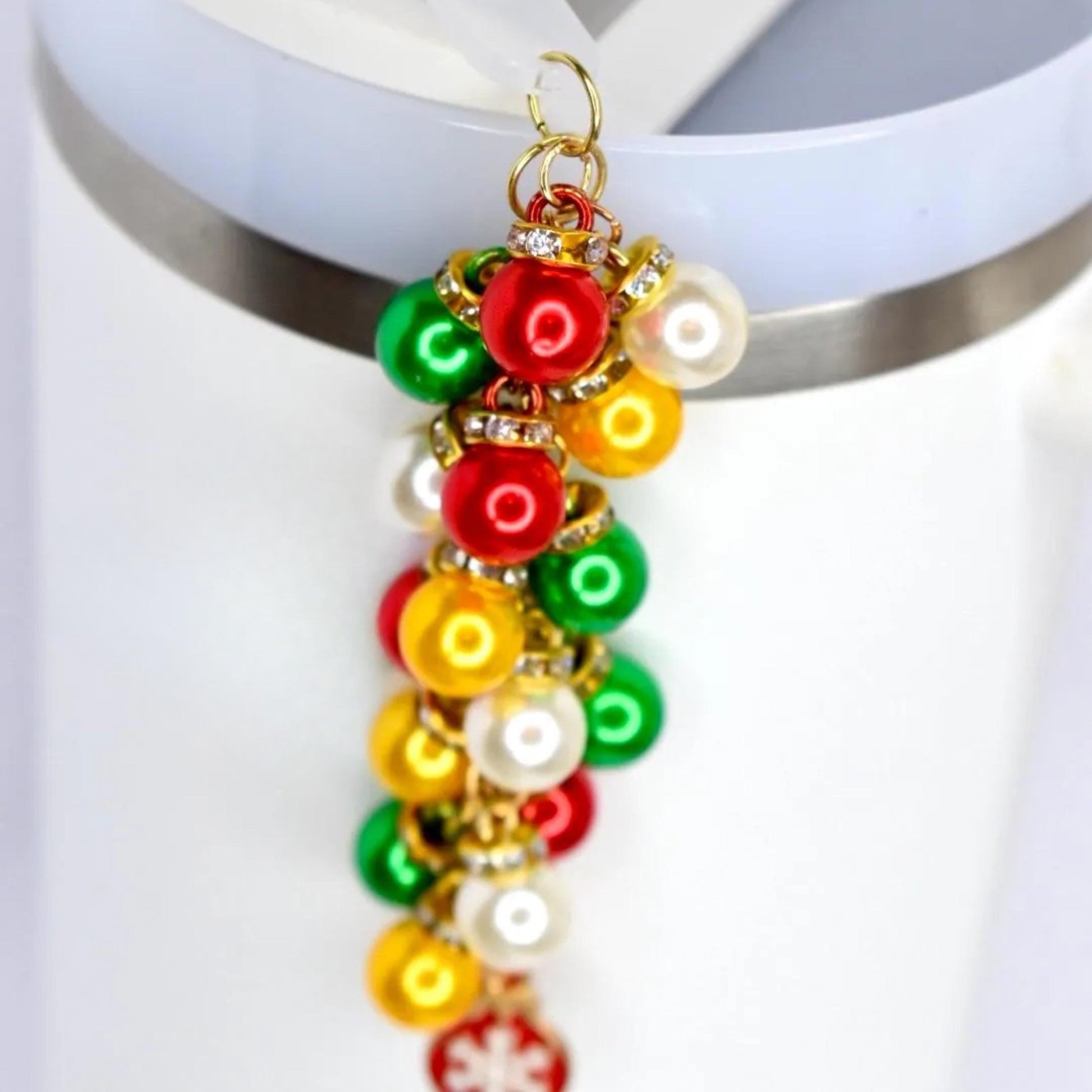 A festive charm featuring a cluster of colorful, round ornaments in red, green, yellow, and white. Each ornament is accented with a gold-colored cap and sparkling rhinestones. The charm is attached to a gold-colored loop, perfect for holiday-themed accessories.