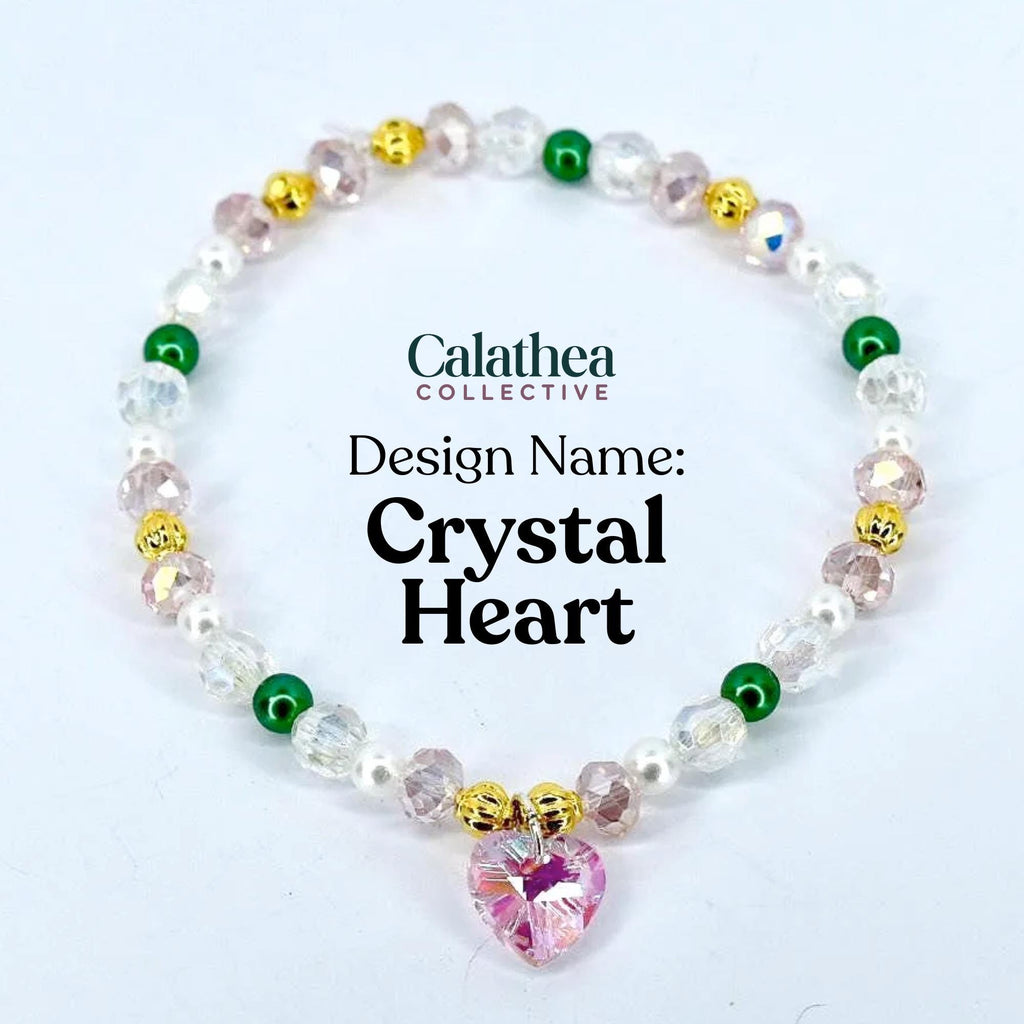A beaded bracelet with a pink crystal heart pendant. The bracelet features clear, pink, green, and gold beads, with the text "Calathea Collective" and "Crystal Heart" visible.