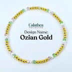 A gold beaded bracelet with pink, green, and white accents. The bracelet is labeled "Ozian Gold" from the Calathea Collective.