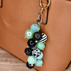 Boho bag charm with green black white pattern beads and lava stone hanging from camel colored purse