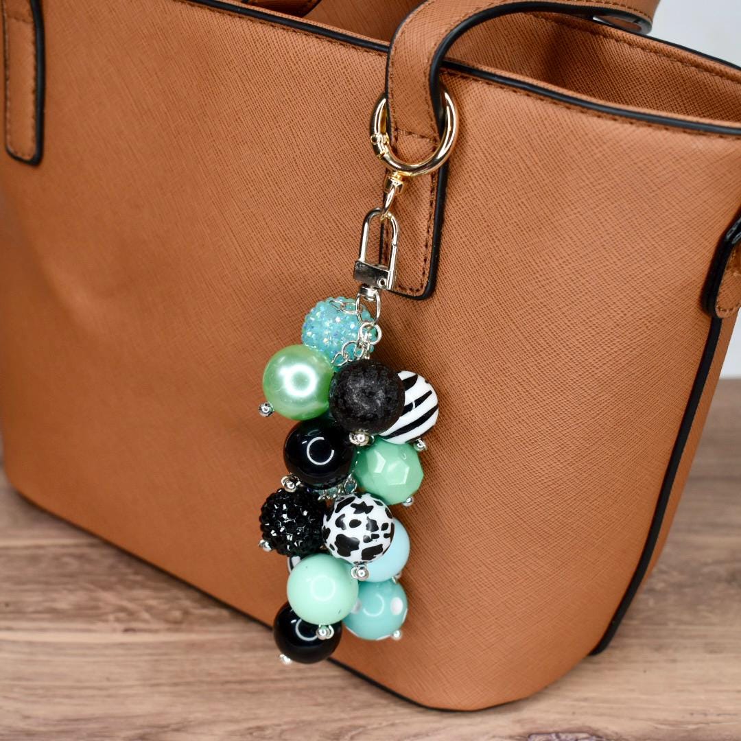 Beaded keychain bag accessory in mint black and white with sparkly accents attached to brown handbag