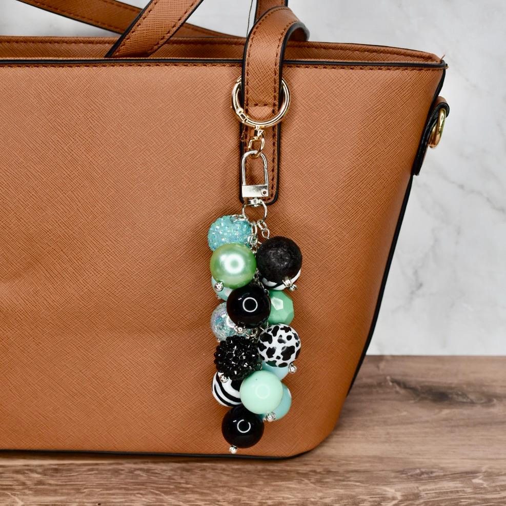 Handmade mint green and black bag charm with chunky beads clipped to tan purse