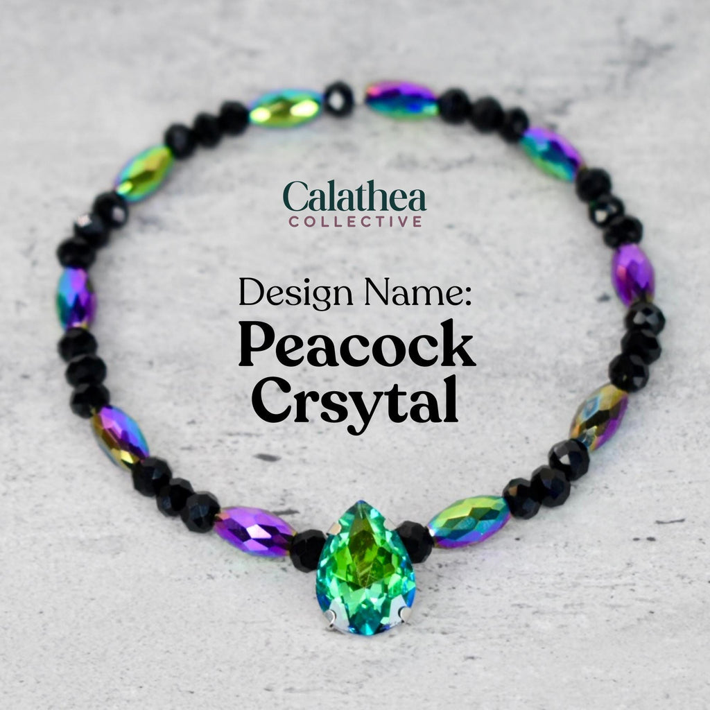 A beaded bracelet with a central green teardrop-shaped crystal. The bracelet features black beads and iridescent oval-shaped beads in shades of purple, green, and blue. The text "Calathea Collective" and "Peacock Crsytal" are visible.
