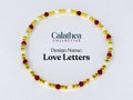 A gold-colored beaded bracelet with red and white beads. The bracelet is circular and features the text "Love Letters" and the Calathea Collective logo.