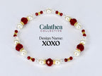 A beaded bracelet featuring alternating white faux pearls, faceted red beads, and small gold-colored beads. The bracelet is labeled "Design Name: XOXO" and includes the "Calathea Collective" logo.
