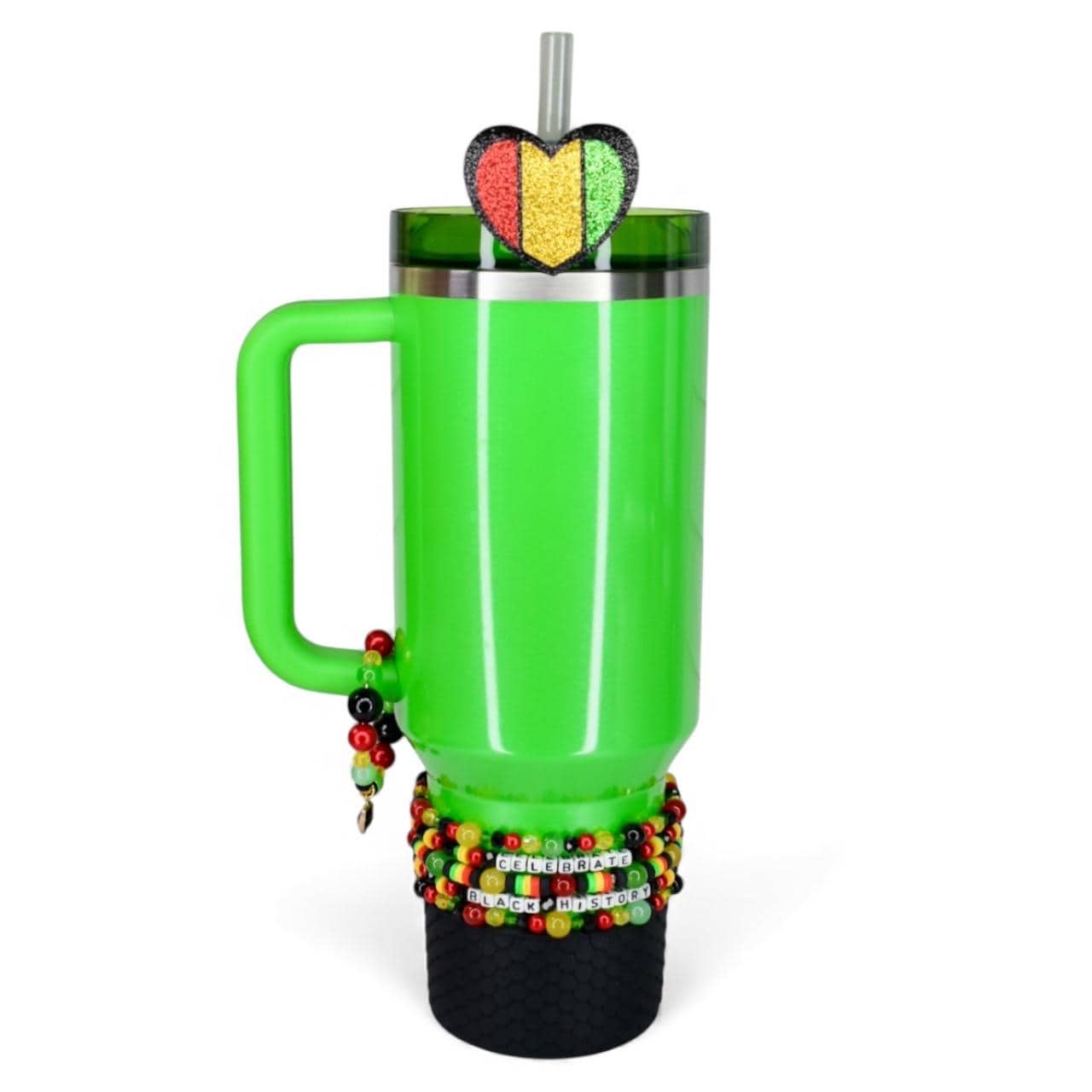A bright green tumbler with a handle, adorned with a heart-shaped glitter accent in red, yellow, and green. The tumbler is decorated with beaded bracelets and the words "Celebrate Black History". Includes a straw.