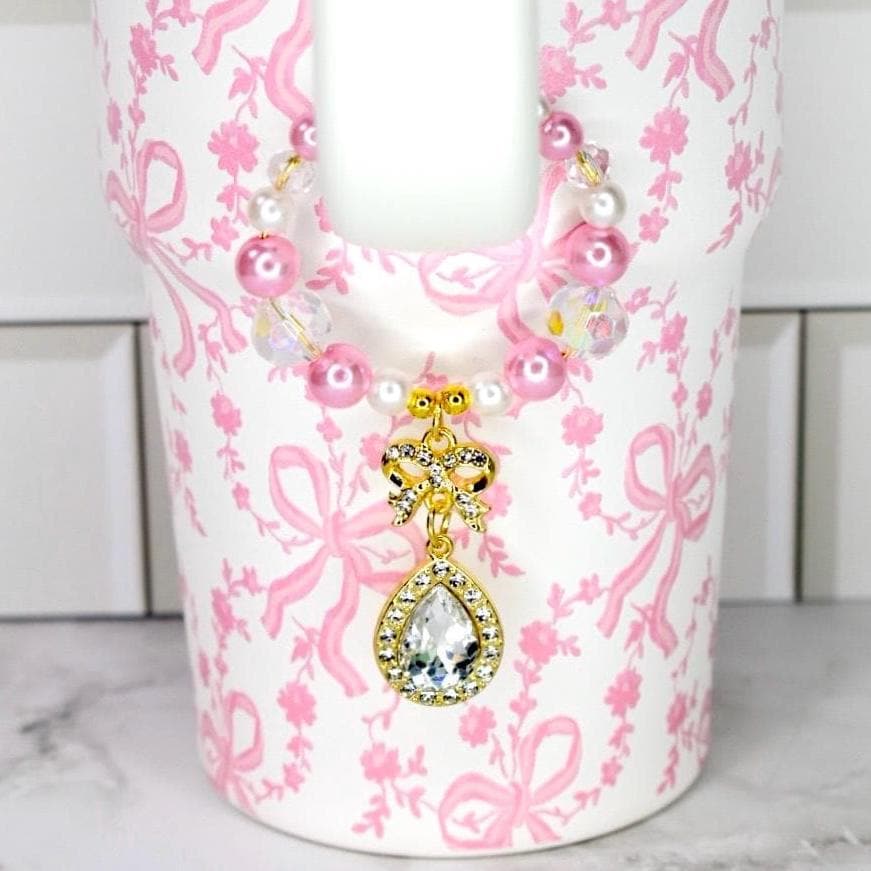 Coquette Bow Stanley tumbler with pink faux pearl and crystal handle charm with a gold bow and tear drop sparkling gem drop charm.