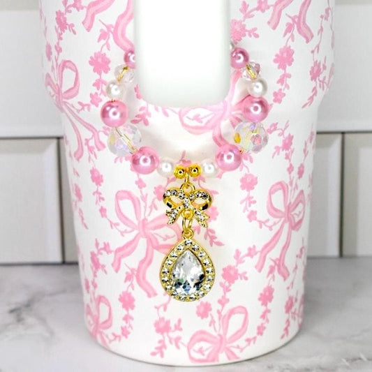 Coquette Bow Stanley tumbler with pink faux pearl and crystal handle charm with a gold bow and tear drop sparkling gem drop charm.
