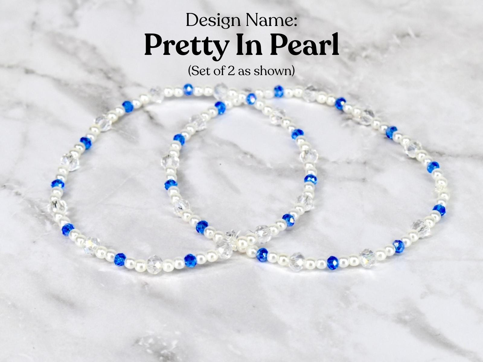 Two bracelets with the design name "Pretty In Pearl". Each bracelet features white pearls, clear crystals, and blue beads. The bracelets are displayed on a white and gray marble surface.