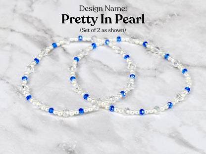 Two bracelets with the design name "Pretty In Pearl". Each bracelet features white pearls, clear crystals, and blue beads. The bracelets are displayed on a white and gray marble surface.