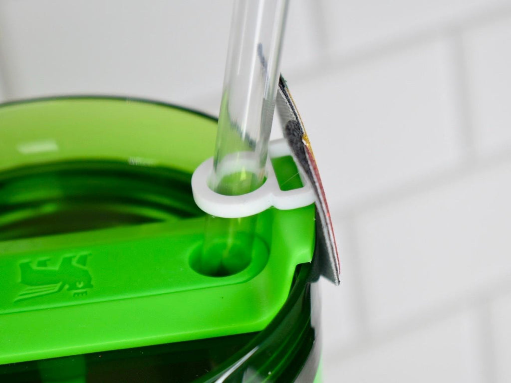 Close-up of a green water bottle with a clear straw and a white straw holder. The bottle has a green lid with a logo. The straw is held in place by a white plastic ring.