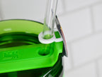 Close-up of a green water bottle with a clear straw and a white straw holder. The bottle has a green lid with a logo. The straw is held in place by a white plastic ring.