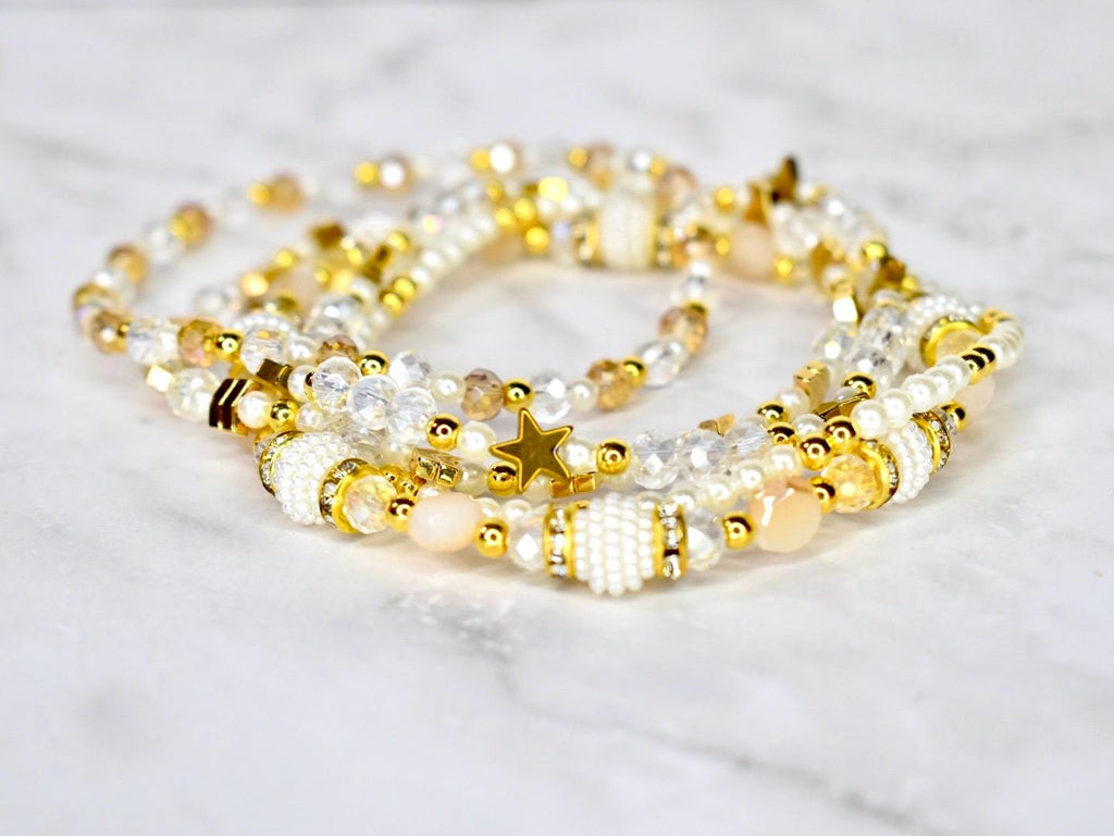 a set of five gold and pearl handmade beaded bracelets featuring star beads, clear crystal beads, and sparkling beige beads. bracelet design inspired by the starlight shimmer Stanley.