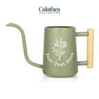 A sage green watering can with long gooseneck spout and wood handle with a white flower bouquet design and 'your text here' below the bouquet in white permanent vinyl.