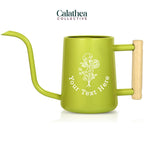 A bright green watering can with long gooseneck spout and wood handle with a white flower bouquet design and 'your text here' below the bouquet in white permanent vinyl.