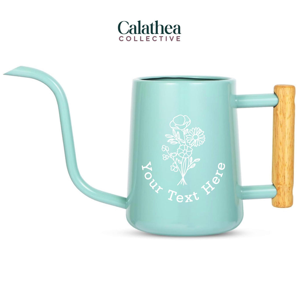 A light blue watering can with long gooseneck spout and wood handle with a white flower bouquet design and 'your text here' below the bouquet in white permanent vinyl.
