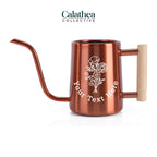 A copper watering can with long gooseneck spout and wood handle with a white flower bouquet design and 'your text here' below the bouquet in white permanent vinyl.