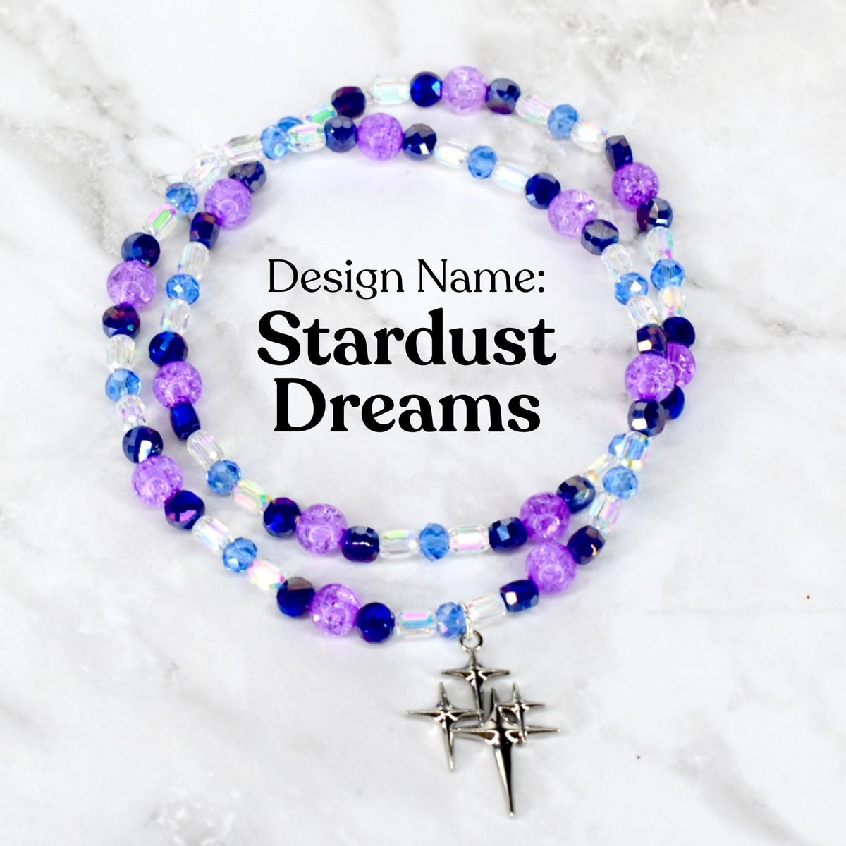 A beaded necklace with the text "Design Name: Stardust Dreams." The necklace features purple, blue, and clear beads, with a silver-colored star pendant. The beads are arranged in multiple strands.
