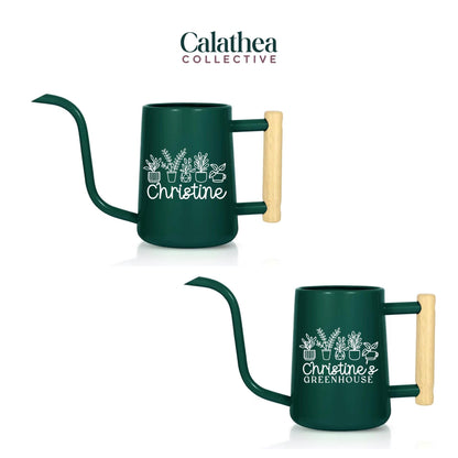 Two dark green metal watering cans with long spouts and wooden handles. Each can has a white graphic of potted plants and the name "Christine" or "Christine's Greenhouse" in white text. The brand name "Calathea Collective" is at the top.