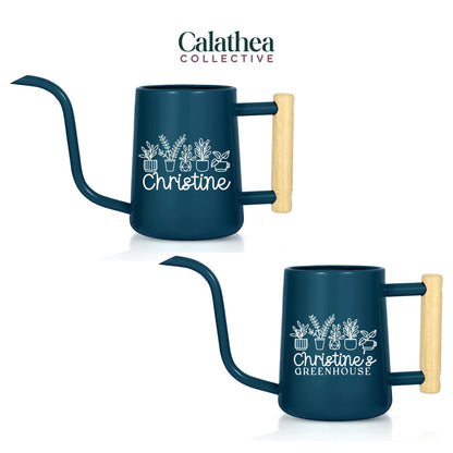 Two dark blue watering cans with long spouts and wooden handles. Each can features a white floral design and the name "Christine" or "Christine's Greenhouse". The "Calathea Collective" logo is at the top.