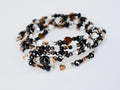 A multi-strand wrap bracelet featuring a mix of black, clear, and bronze-colored beads. The bracelet includes heart-shaped and round beads, with a central black bead accented with silver-colored details. The bracelet is designed to wrap around the wrist multiple times.