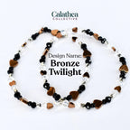 Two beaded bracelets with the text "Design Name: Bronze Twilight". The bracelets feature bronze heart-shaped beads, black beads, and clear crystal beads. The bracelets are from the Calathea Collective.