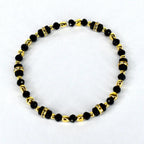 A beaded bracelet featuring black and gold beads. The bracelet has a mix of small, round black beads and larger, rectangular black beads with rhinestone accents. Gold-colored beads separate the black beads.