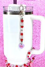 A beaded straw keychain with red, pink, and clear beads, and a silver-tone clasp. The keychain has a purple heart charm that says "Sweet Heart". The keychain is attached to a white tumbler.