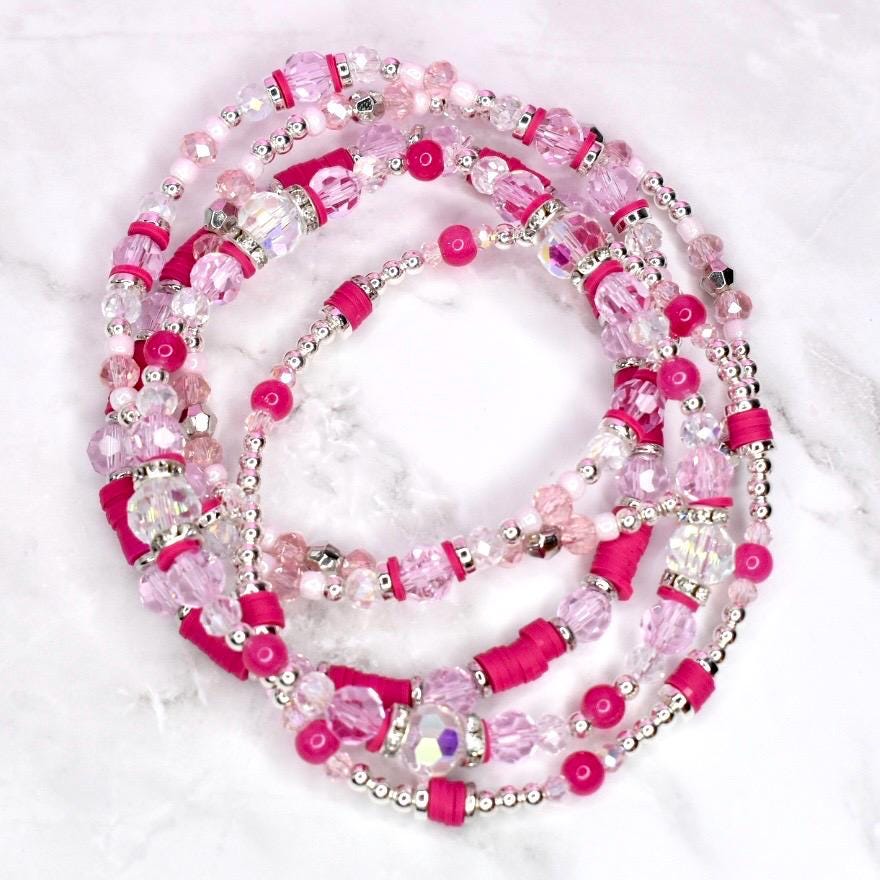 A collection of pink and clear beaded bracelets. The bracelets feature a variety of beads, including small silver beads, clear faceted beads, and larger pink beads. Some sections have bright pink cylindrical beads.