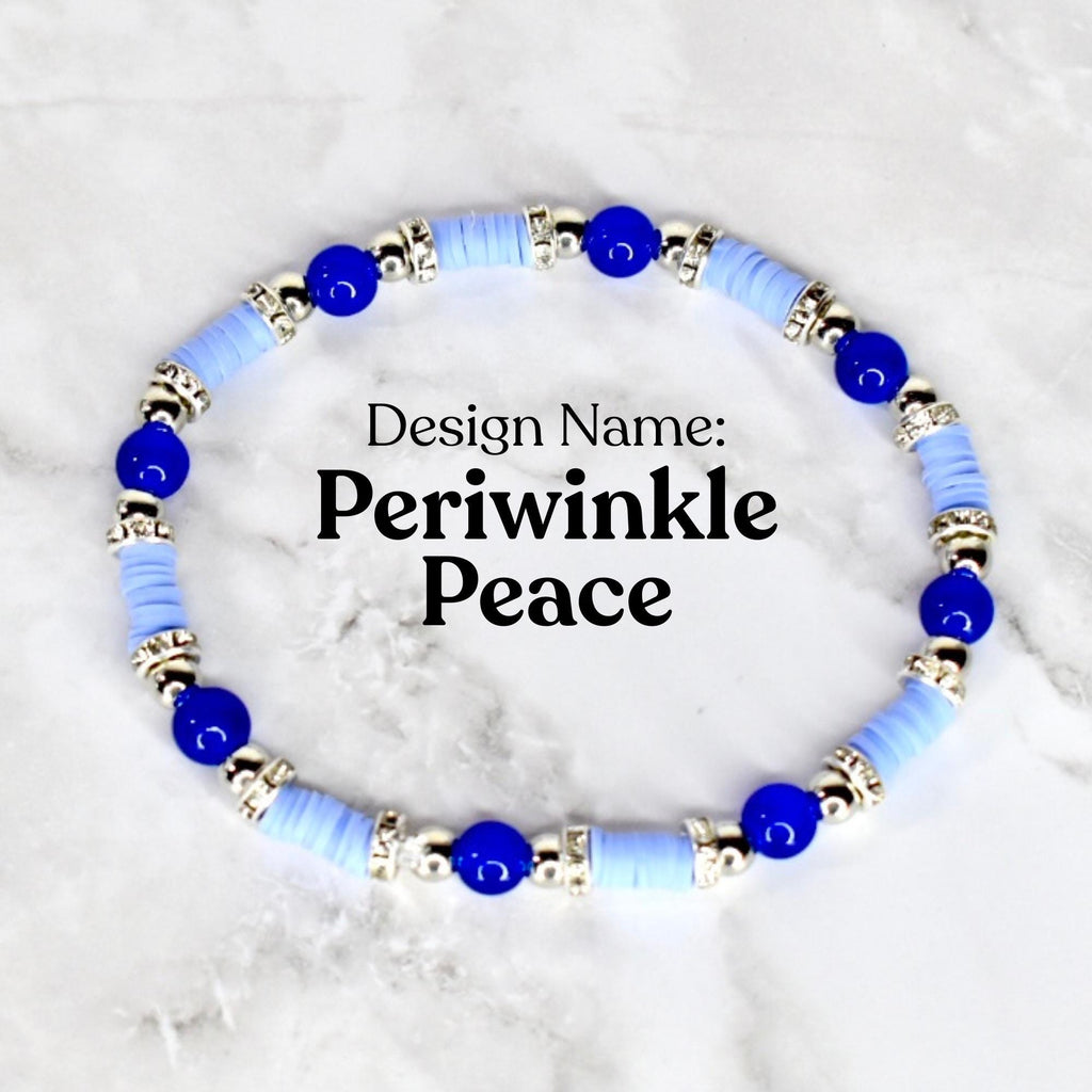 A bracelet with the design name "Periwinkle Peace". The bracelet features light blue disc-shaped beads, interspersed with dark blue spherical beads and silver-colored decorative elements. The bracelet is displayed on a white surface.
