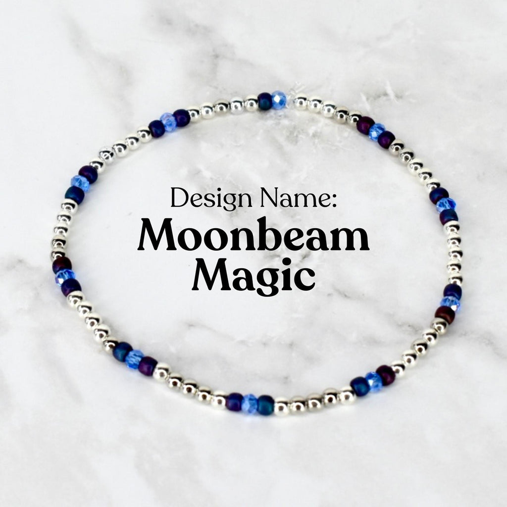 A delicate beaded bracelet featuring small silver beads interspersed with blue and purple beads. The text "Design Name: Moonbeam Magic" is displayed in black font.