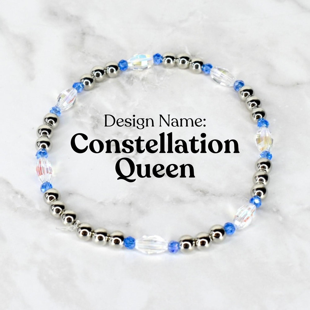 A beaded bracelet with the text "Design Name: Constellation Queen". The bracelet features silver-colored beads, blue beads, and clear, iridescent crystal beads. The bracelet is circular and sits on a white and gray marble surface.