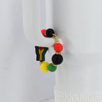 A colorful beaded bracelet featuring red, black, yellow, and green beads. The bracelet includes a charm with a black fist. Gold-colored accents are present throughout the bracelet.