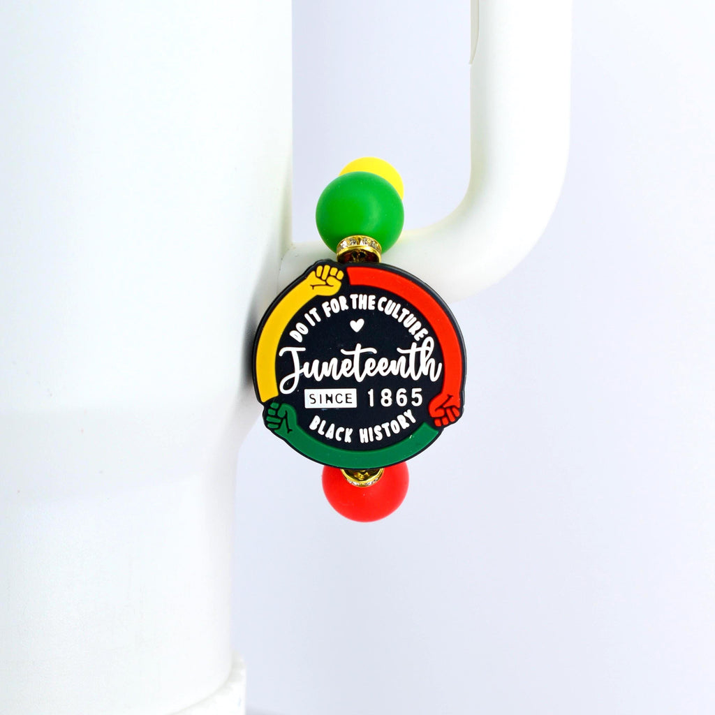 A Juneteenth-themed charm with a black, red, yellow, and green color scheme. The charm features the text "Do it for the culture" and "Juneteenth Since 1865 Black History". The charm is attached to a beaded strand with green, yellow, and red beads.