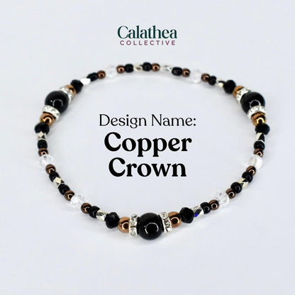 A beaded bracelet with the text "Copper Crown." The bracelet features black, clear, silver, and copper-colored beads. The bracelet is from the Calathea Collective.