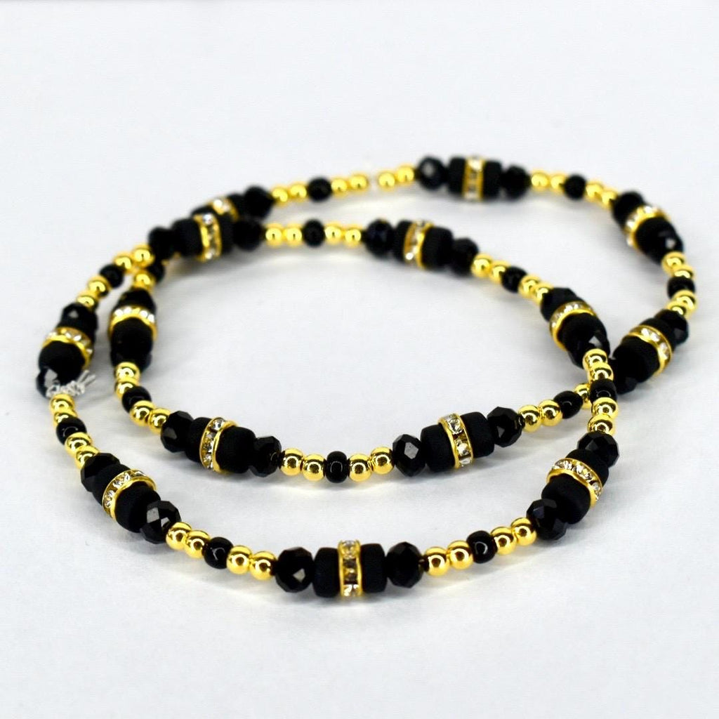 Two beaded bracelets. The bracelets feature black beads interspersed with gold-colored beads and gold-colored spacers with clear rhinestones. The bracelets are displayed on a white background.