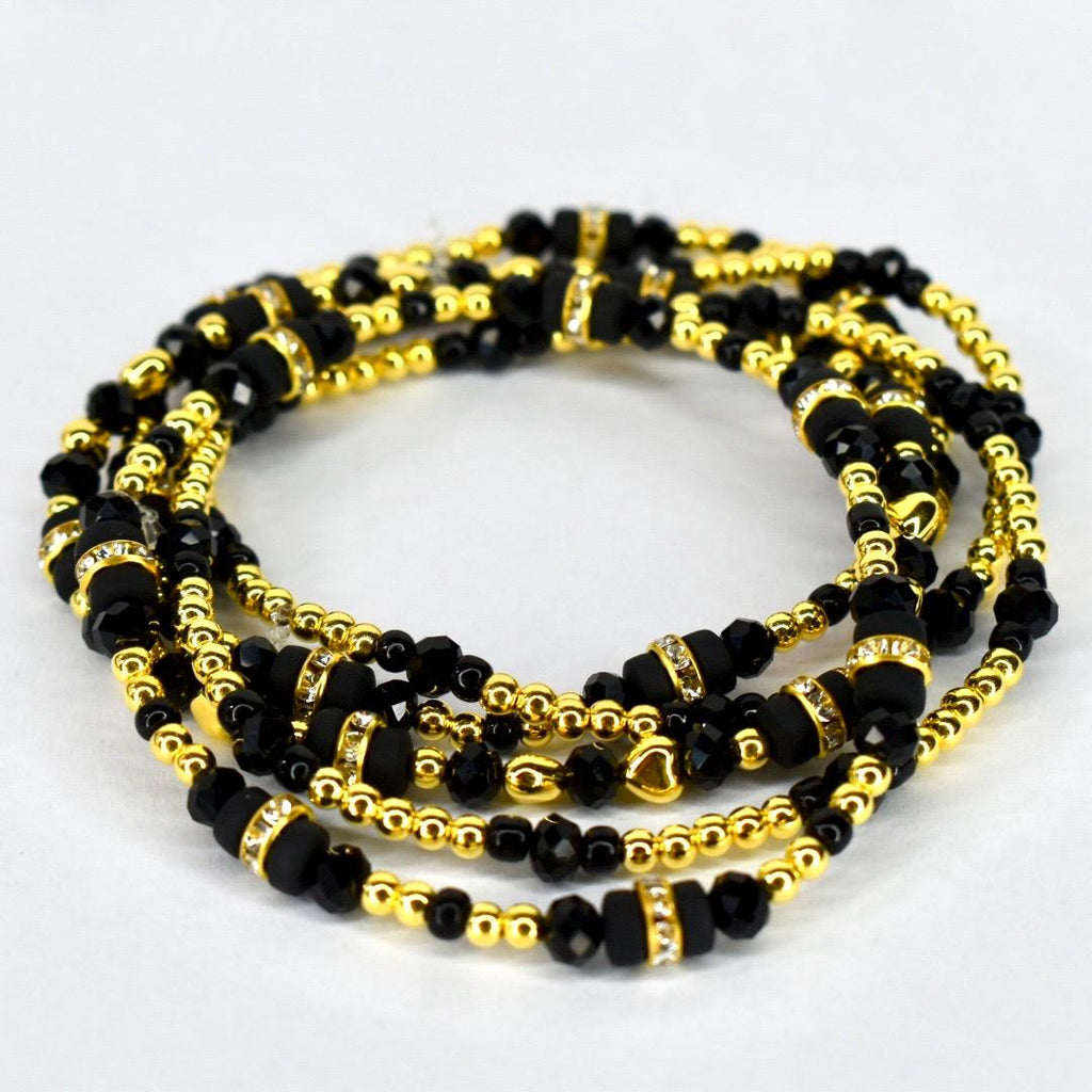 Four strands of black and gold beaded jewelry. The strands are intertwined, showcasing a mix of small gold beads, larger black beads, and gold-toned spacers with clear crystal accents. The jewelry is displayed on a white background.