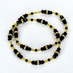 A set of two black beaded bracelets with gold-colored accents and rhinestone-studded spacers. The bracelets feature small, round gold beads and larger, faceted black beads. The design is symmetrical, with the beads arranged in a repeating pattern.