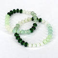 Two beaded bracelets with a gradient of green and white beads. The beads are strung on a green cord, creating a delicate and elegant accessory. The bracelets are displayed on a white background.