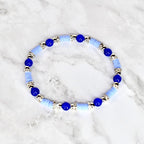 A light blue and silver beaded bracelet. The bracelet features alternating light blue disc-shaped beads and silver-colored cylindrical beads. Dark blue round beads are interspersed throughout the design.
