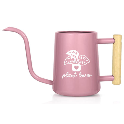 A pink watering can with a long, slender spout and a wooden handle. The can features a white graphic of a plant in a pot with the words "plant lover" below it. The watering can is designed for indoor plant care.