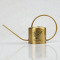 A gold metal watering can with a long spout and a curved handle. The can features a black floral design and the name "Amanda" in script. The watering can is designed for indoor or outdoor plant care.